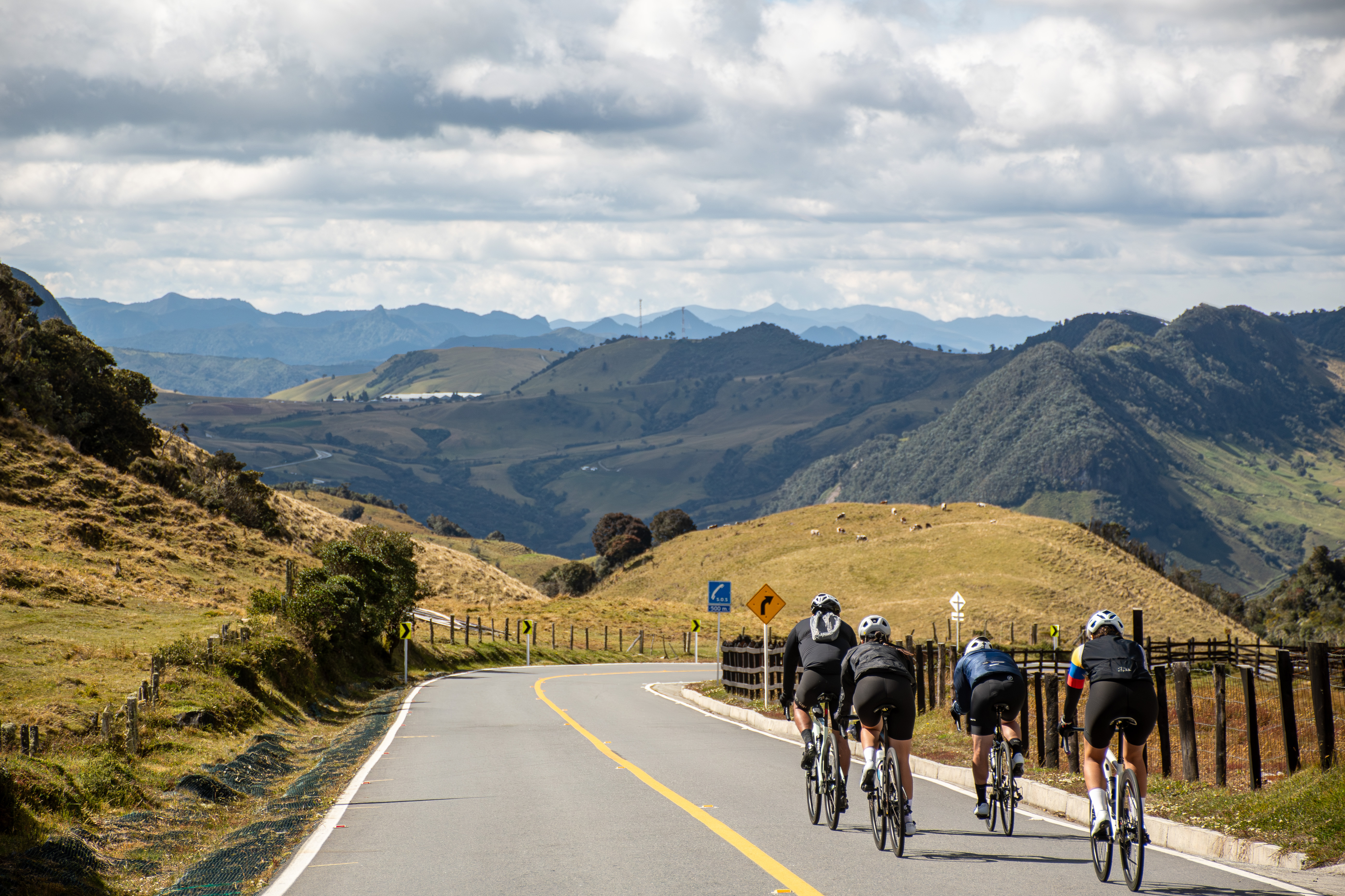 Group of cyclists riding in formation on a paved mountain road on a women's cycling tour in Colombia.
