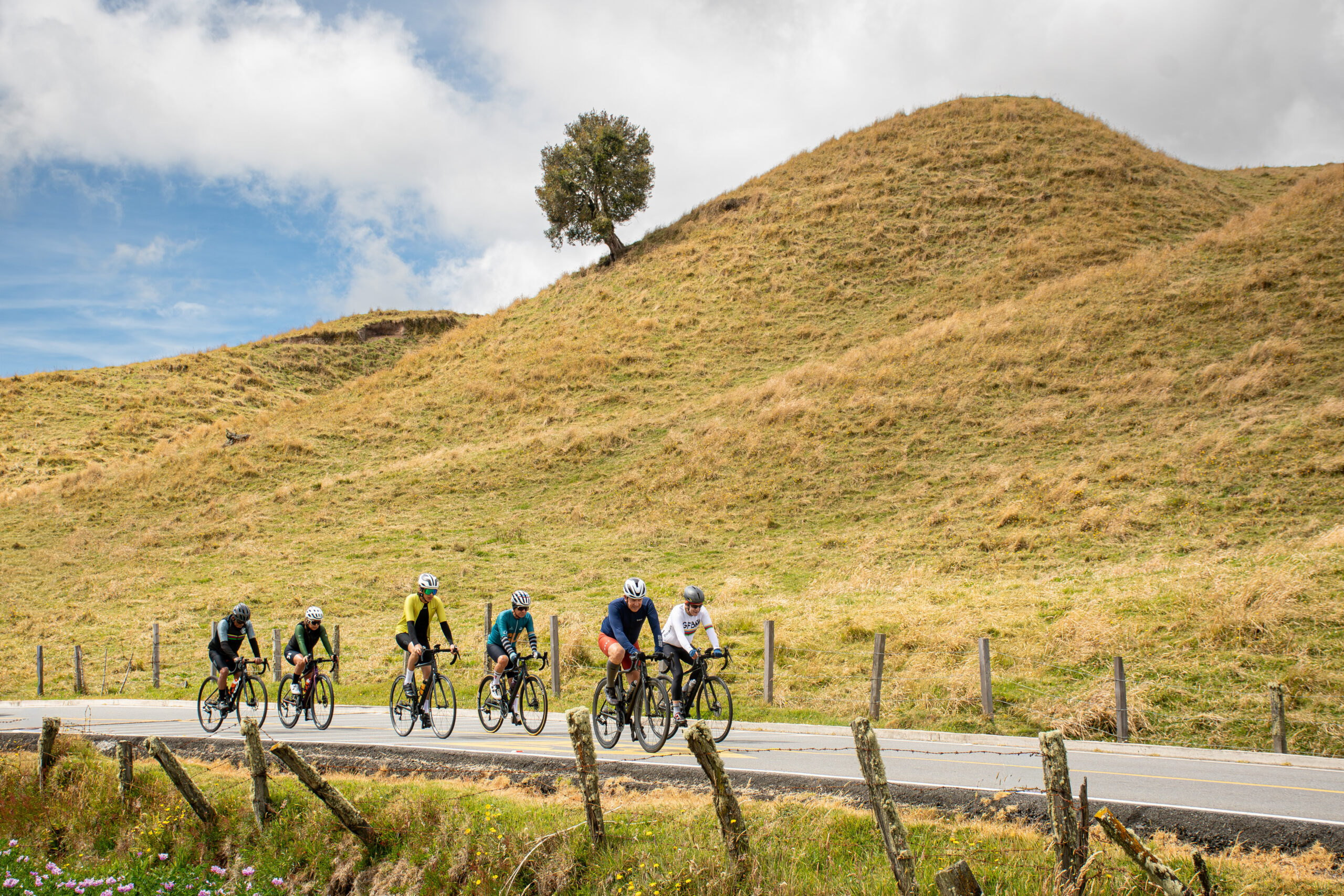 Group of cyclists riding together on a paved road during an 8-week training plan for Alto de Letras.